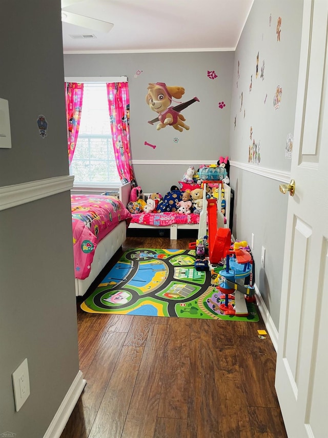 bedroom with baseboards, visible vents, wood finished floors, and crown molding