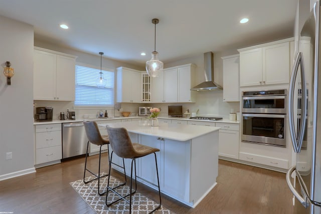 kitchen with a center island, wall chimney exhaust hood, white cabinets, and stainless steel appliances