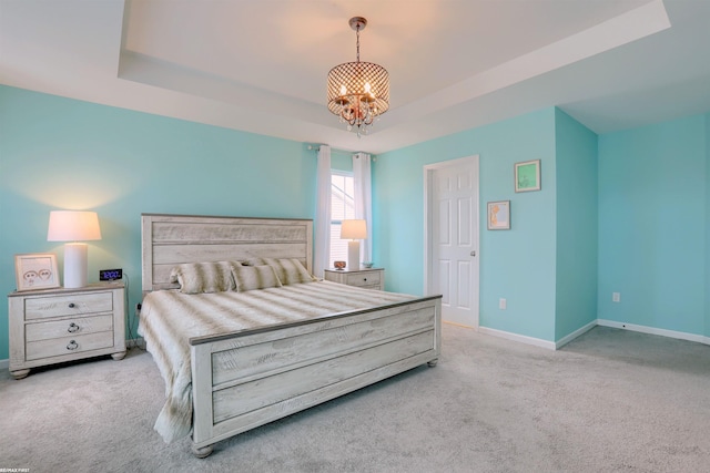 carpeted bedroom with an inviting chandelier, a raised ceiling, and baseboards