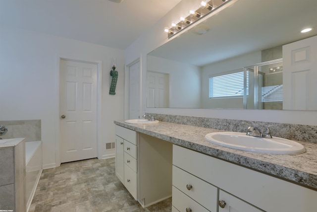 full bath featuring a garden tub, double vanity, a sink, and a shower stall