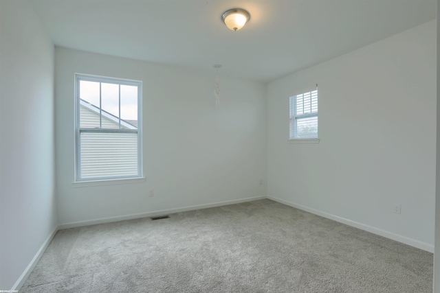 carpeted empty room featuring visible vents and baseboards