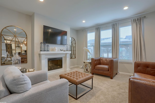 living area with a glass covered fireplace, plenty of natural light, recessed lighting, and baseboards