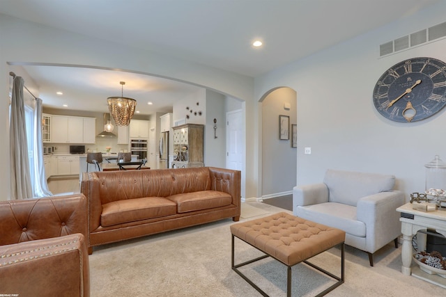 living area with recessed lighting, arched walkways, visible vents, and light carpet