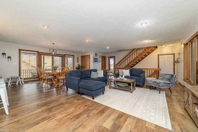living room featuring light wood-type flooring, a textured ceiling, and plenty of natural light