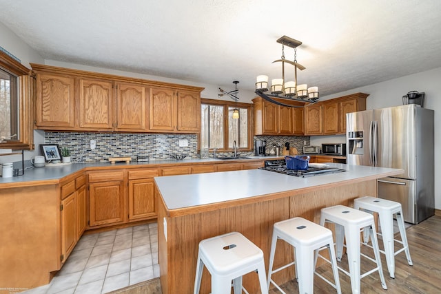 kitchen with a sink, appliances with stainless steel finishes, a breakfast bar, a kitchen island, and a wealth of natural light