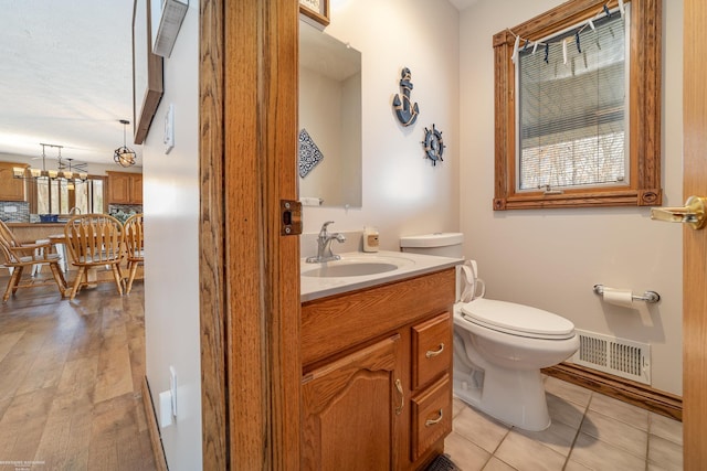 bathroom with visible vents, an inviting chandelier, toilet, vanity, and tile patterned flooring