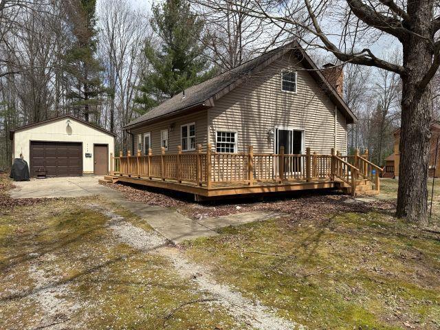 back of house featuring an outdoor structure, a detached garage, and a deck