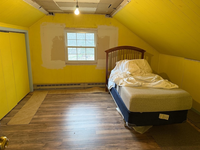 bedroom featuring a baseboard heating unit, a closet, track lighting, vaulted ceiling, and wood finished floors