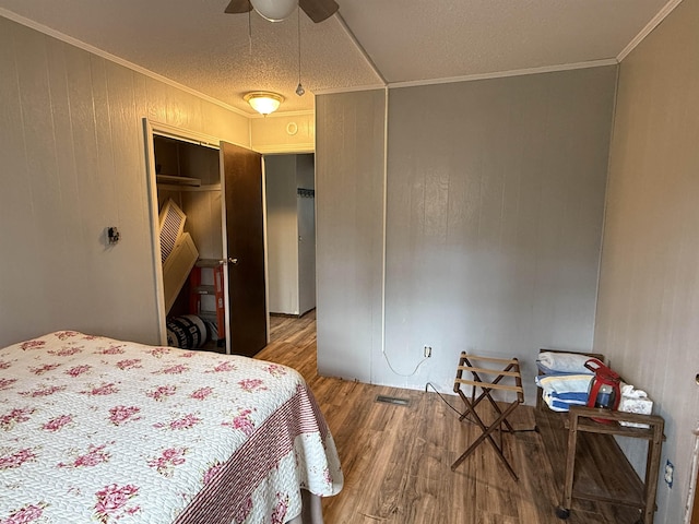 bedroom featuring a closet, ceiling fan, visible vents, ornamental molding, and wood finished floors