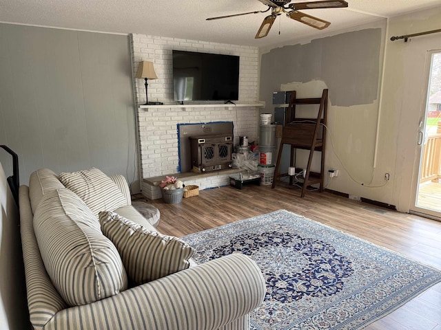 living room featuring wood finished floors, ceiling fan, and a textured ceiling