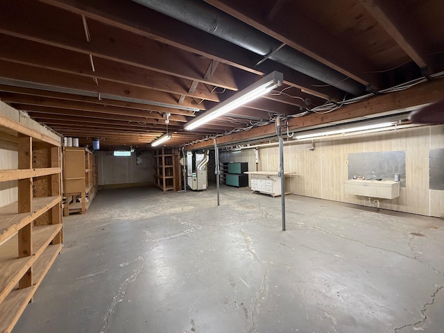 unfinished basement with fridge, heating unit, and a sink