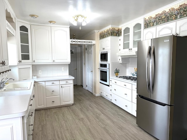 kitchen featuring a sink, stainless steel appliances, light wood-type flooring, backsplash, and light countertops