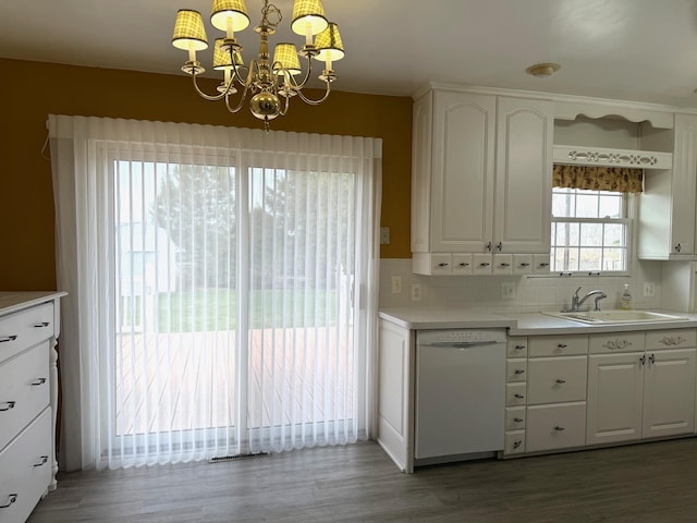kitchen featuring tasteful backsplash, a chandelier, white dishwasher, white cabinets, and a sink