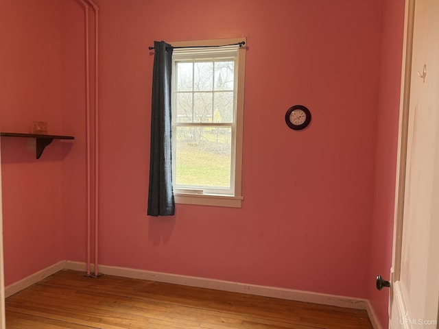 unfurnished room featuring baseboards, a wealth of natural light, and wood-type flooring