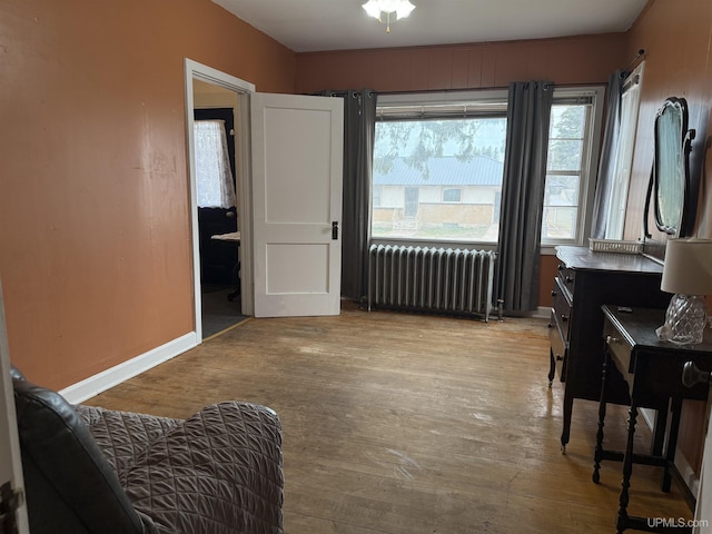 living area featuring radiator, hardwood / wood-style floors, and baseboards