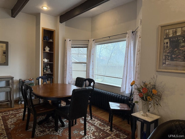 dining room with beam ceiling and wood finished floors