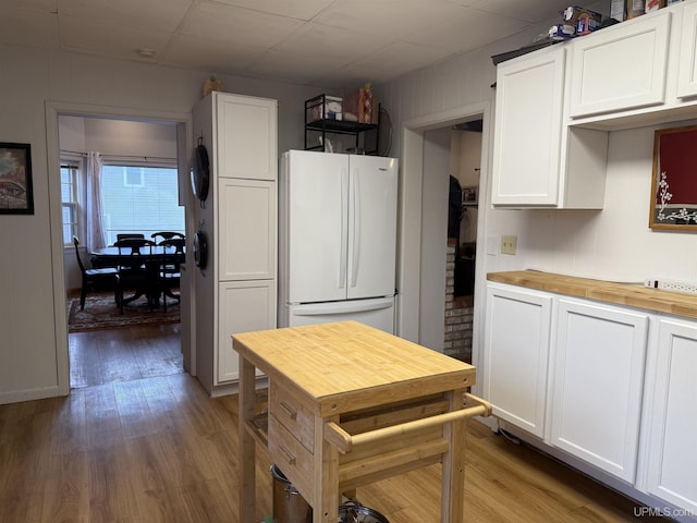 kitchen with wood counters, freestanding refrigerator, wood finished floors, and white cabinetry