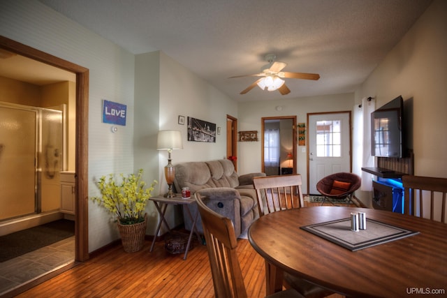 dining space with wood-type flooring, a ceiling fan, and baseboards