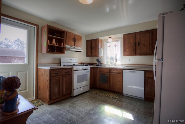 kitchen with white appliances, open shelves, under cabinet range hood, brown cabinets, and a sink