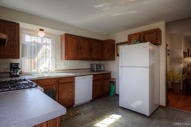 kitchen with light countertops, a sink, brown cabinets, and white appliances