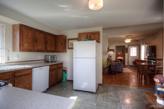kitchen with brown cabinets, a sink, light countertops, white appliances, and a ceiling fan