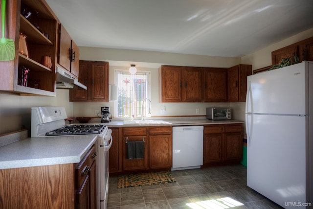 kitchen with a sink, under cabinet range hood, white appliances, light countertops, and a toaster