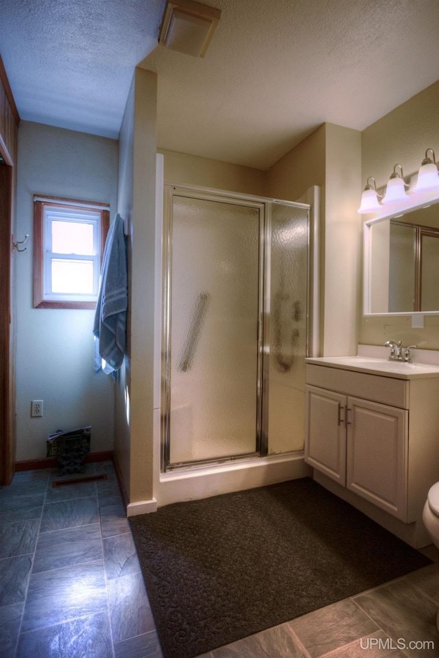 bathroom with toilet, a textured ceiling, a shower stall, and vanity