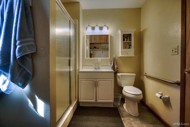bathroom featuring baseboards, a stall shower, toilet, and vanity