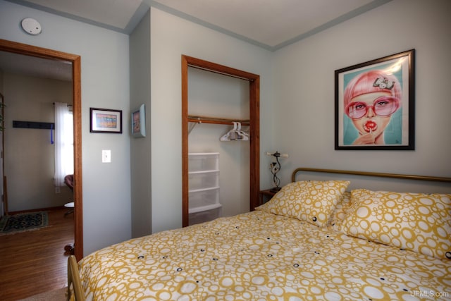 bedroom featuring baseboards, wood finished floors, and a closet