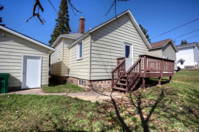 back of property with a deck, a chimney, and a yard