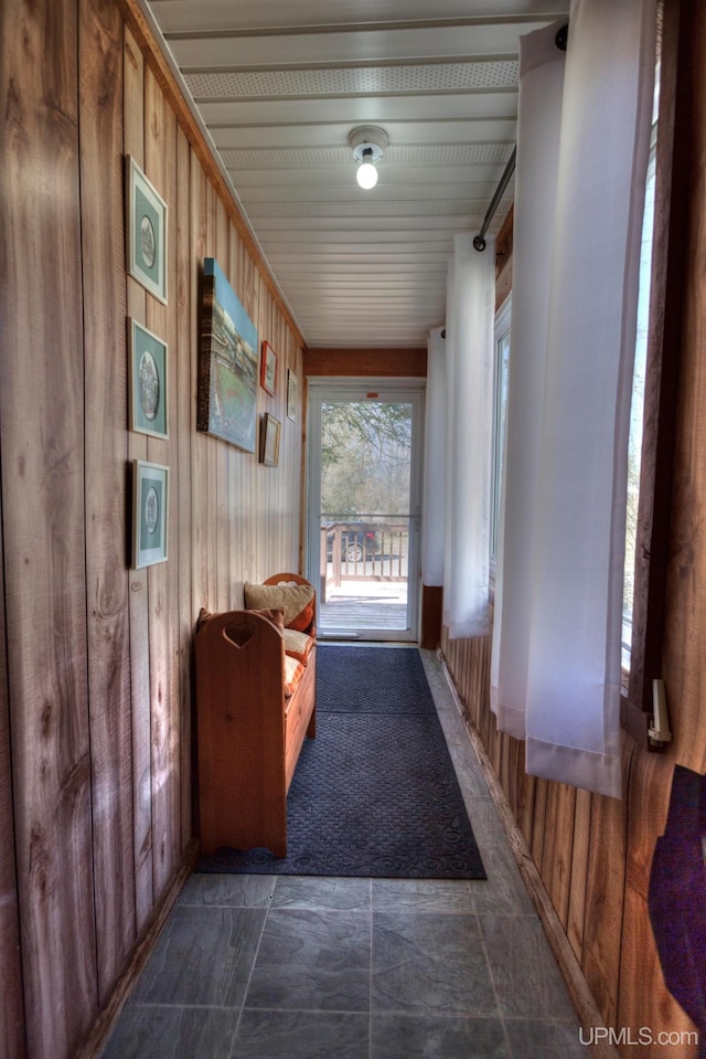 entryway with wood walls and stone finish flooring