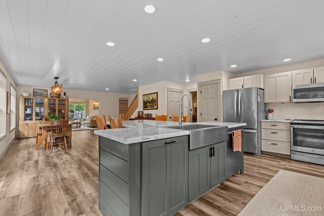 kitchen featuring light wood-style flooring, a sink, appliances with stainless steel finishes, recessed lighting, and a center island with sink