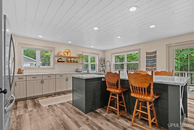 kitchen featuring recessed lighting, freestanding refrigerator, an island with sink, and a healthy amount of sunlight