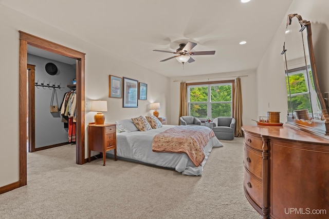 bedroom featuring a spacious closet, a ceiling fan, multiple windows, and light colored carpet