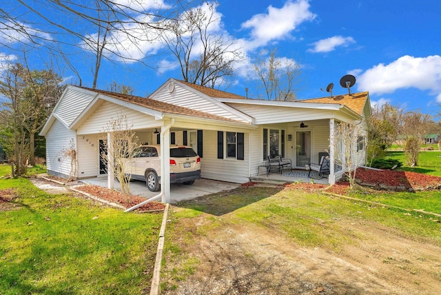 rear view of house featuring an attached carport, ceiling fan, dirt driveway, and a lawn