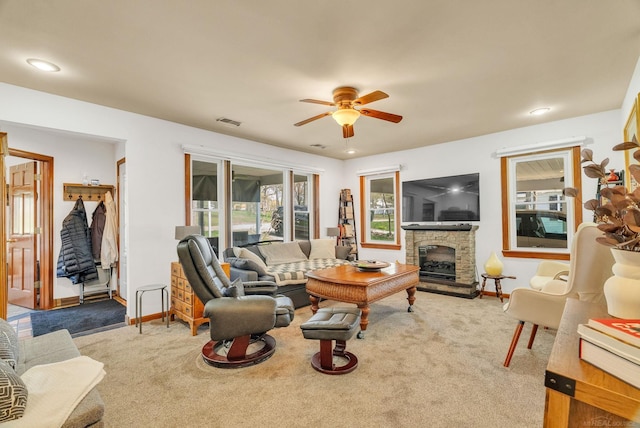 carpeted living area featuring recessed lighting, ceiling fan, a stone fireplace, baseboards, and visible vents