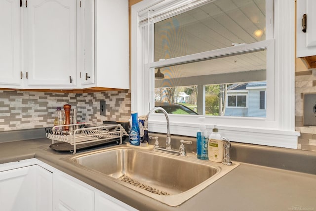 interior details with white cabinets, backsplash, and a sink