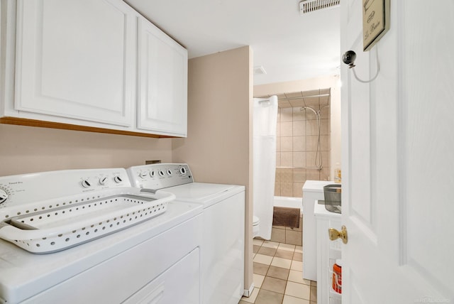 clothes washing area with light tile patterned flooring, visible vents, separate washer and dryer, and cabinet space