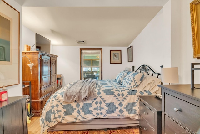 bedroom featuring light wood finished floors, visible vents, and vaulted ceiling