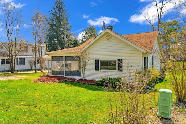 back of house with roof with shingles, a yard, and a sunroom