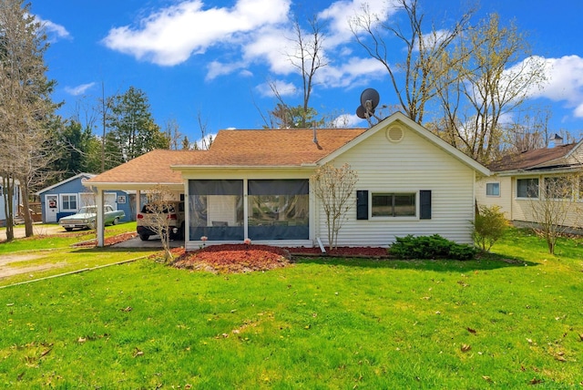 rear view of property featuring roof with shingles, a carport, a yard, and a sunroom