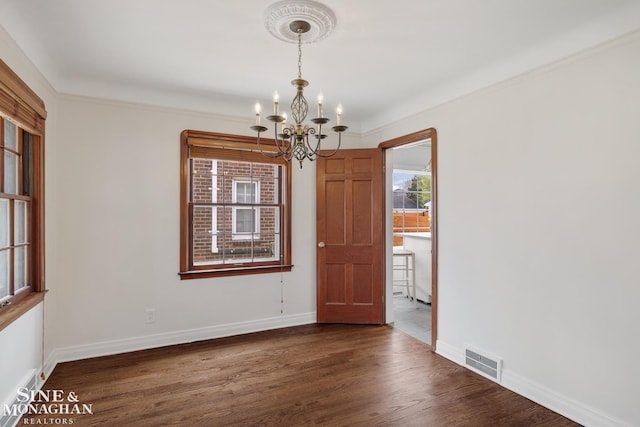 unfurnished dining area with a chandelier, ornamental molding, baseboards, visible vents, and dark wood-type flooring