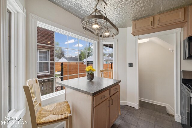 kitchen with baseboards, dark tile patterned floors, a kitchen island, and an ornate ceiling