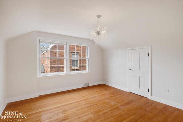 additional living space featuring baseboards, visible vents, light wood-style floors, and lofted ceiling