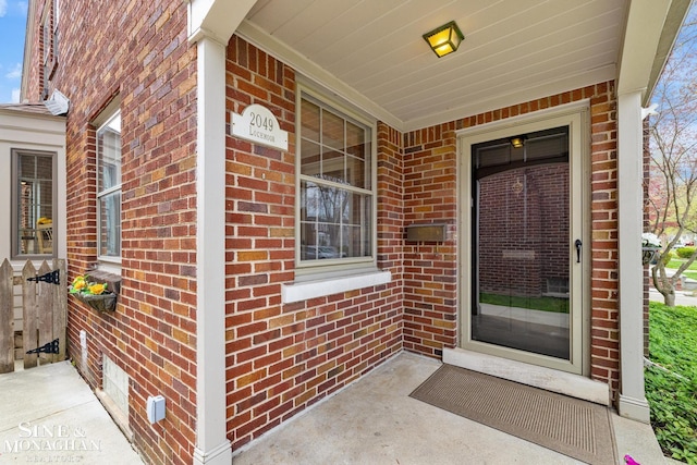entrance to property with covered porch and brick siding