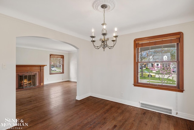 unfurnished dining area featuring visible vents, plenty of natural light, a chandelier, and arched walkways