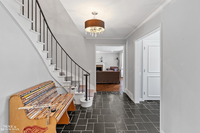 foyer entrance with crown molding, baseboards, stairway, and a fireplace