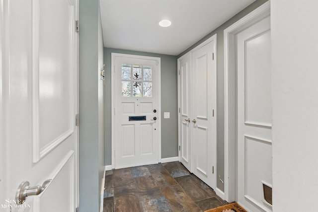 doorway to outside featuring stone finish floor and baseboards