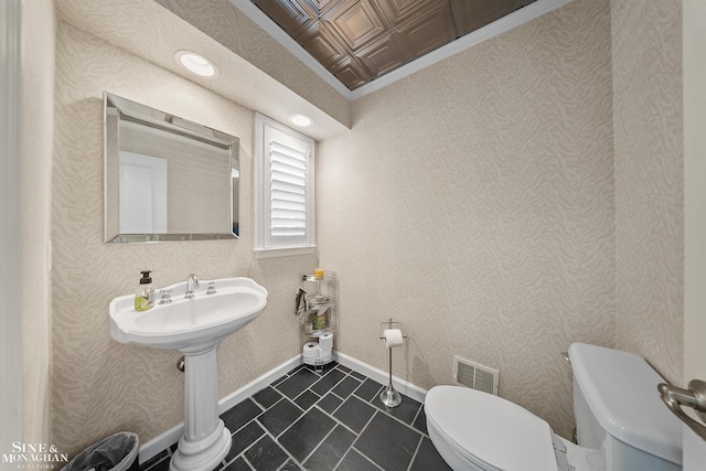 half bath featuring tile patterned flooring, toilet, baseboards, visible vents, and ornamental molding