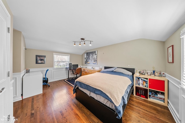 bedroom with wainscoting, wood finished floors, and lofted ceiling